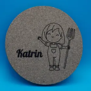 Personalisierbarer Untersetzer aus Kork mit niedlicher Gravur eines lächelnden Mädchens in Latzhose und Heugabel sowie einem individuell wählbaren Namen, hier „Katrin“. Perfekt als originelle Tischdeko, kreatives Geschenk oder persönliche Erinnerung an besondere Anlässe.