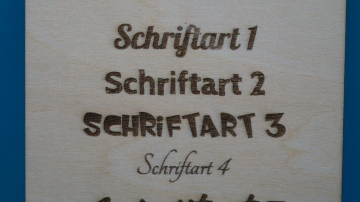 Nahaufnahme der oberen vier Gravuren auf Holz mit den Schriftarten 1 bis 4. Die Schriften wirken verspielt, schlicht, comicartig und elegant – ideal für individuelle Gravuren mit Charakter.