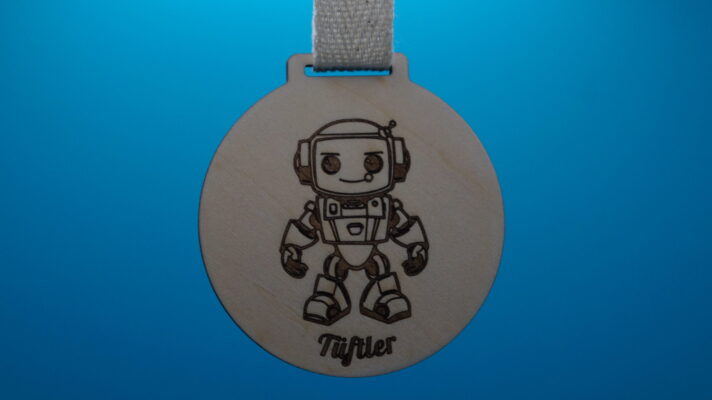 Medaille für Kinder aus Holz mit süßem Roboter und der Aufschrift Tüftler
