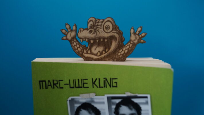 Lesezeichen witzige Tiere - überraschte Gesichter, das Krokodilschaut aus einem Taschenbuch heraus, Nahaufnahme.